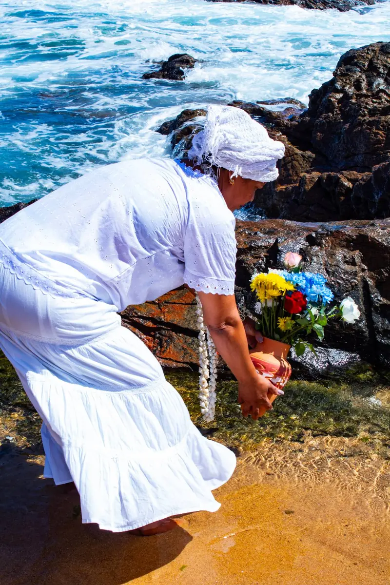 Mãe Iara entregando oferenda nas pedras à beira-mar