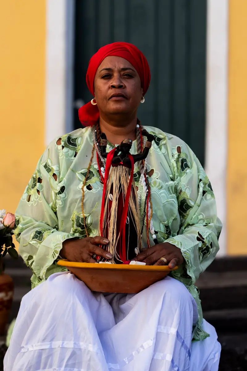 Retrato de Mãe Iara de Iansã de turbante vermelho, sentada com uma gamela